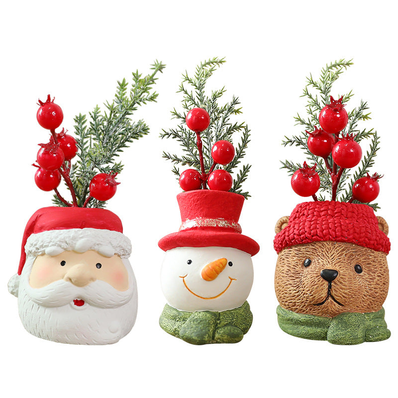 Three decorative pots shaped like a Santa Claus, snowman, and bear with Christmas trees and red berries on top.
